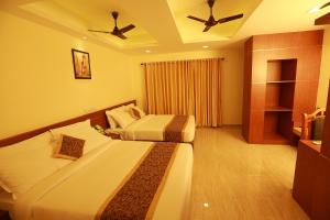 ein Hotelzimmer mit 2 Betten und einem Deckenventilator in der Unterkunft The Crescent Suites in Ernakulam