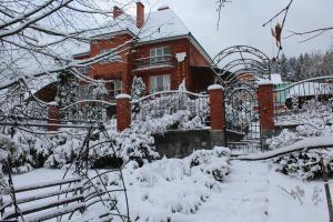 een huis bedekt met sneeuw met een hek bij Zolotoie Runo in Skhidnitsa