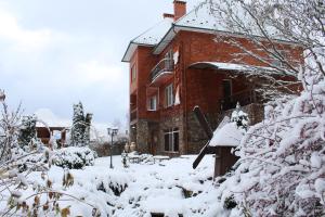 een rood bakstenen huis met sneeuw op de grond bij Zolotoie Runo in Skhidnitsa