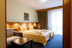 ein Hotelzimmer mit einem Bett und einem Stuhl in der Unterkunft Kap House Family Hotel in Bansko