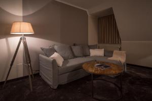 a living room with a couch and a table with a lamp at Hotel Stadt Aurich in Aurich