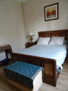 - une chambre avec un grand lit en bois et une couverture bleue dans l'établissement Chez Sylvie, à Sainte-Foy-lès-Lyon