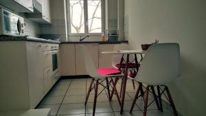 - une cuisine avec des chaises blanches, une table et un évier dans l'établissement Basel Charme Apartments, à Bâle