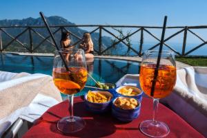 twee glazen wijn en snacks op een tafel naast een zwembad bij Garden Hotel in Ravello