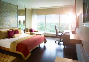 a bedroom with a bed and a desk and a window at Vivanta Coimbatore in Coimbatore