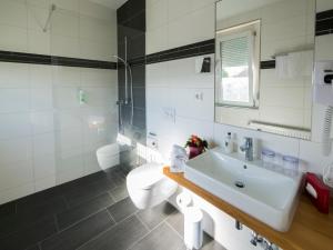 een witte badkamer met een wastafel en een toilet bij Hotel Löwen Garni - B&B in Rust