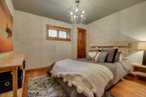 Schlafzimmer mit einem Bett, einem Schreibtisch und einem Kronleuchter in der Unterkunft Log Cabin Home with Lake and Mountain view by Reserver.ca in Sainte-Adèle