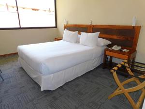 ein Schlafzimmer mit einem großen weißen Bett und einem Telefon in der Unterkunft Hotel Mar Andino in Rancagua