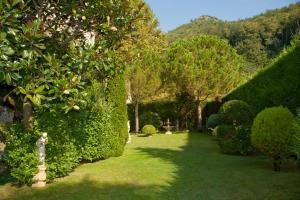 un giardino con siepi verdi, alberi e erba di Hotel Scapolatiello a Cava deʼ Tirreni