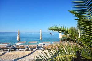 - un groupe de chaises longues et de parasols sur une plage dans l'établissement Hotel Jona, à Podstrana