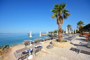 - une plage avec des chaises, un palmier et l'océan dans l'établissement Hotel Jona, à Podstrana