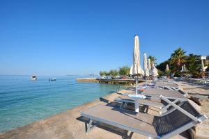 - une rangée de chaises longues et de parasols sur une plage dans l'établissement Hotel Jona, à Podstrana