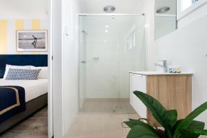 een badkamer met een douche, een bed en een wastafel bij Blue Heron Boutique Motel in Gold Coast