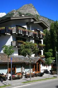 ein großes Gebäude mit Balkonen und Bäumen davor in der Unterkunft Hotel Les Jumeaux Courmayeur in Courmayeur