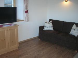 a living room with a black couch and a flat screen tv at Kompatscherhof in Castelrotto