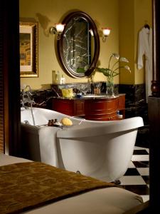 a bathroom with a tub and a sink and a mirror at The Majestic Malacca Hotel - Small Luxury Hotels of the World in Melaka