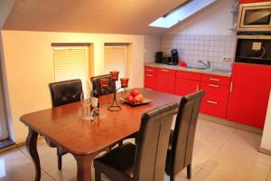 une cuisine avec une table en bois, des chaises et des armoires rouges dans l'établissement Oppenheimstrasse 2, à Eisenach