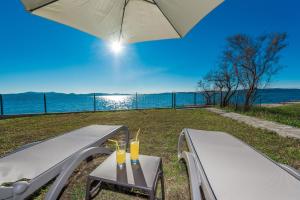 um par de bancos com bebidas sobre eles com um guarda-chuva em Villa Amfora - First row by the sea em Bibinje