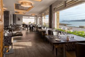 een restaurant met tafels en stoelen en uitzicht op de oceaan bij Hostellerie De La Mer in Crozon