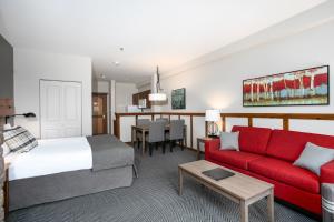 ein Hotelzimmer mit einem Bett und einem roten Sofa in der Unterkunft Tour des Voyageurs in Mont-Tremblant