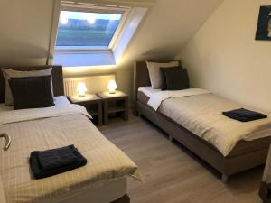 two beds in a small room with a window at Maaszicht in Maasmechelen