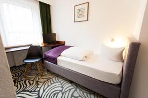 a bedroom with a bed and a desk and a window at Hotel Atlanta in Hannover