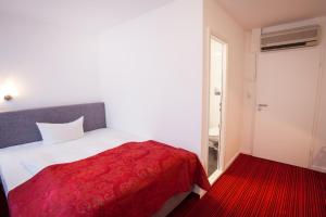 a bedroom with a bed with a red blanket at Hotel Atlanta in Hannover