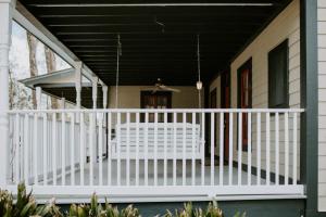 eine Veranda mit einem weißen Geländer und einem schwarzen Dach in der Unterkunft Maison Mouton Bed & Breakfast in Lafayette