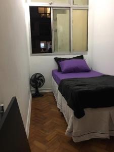 Un dormitorio con una cama con sábanas moradas y una ventana en Adonai Copacabana Rooms 01, en Río de Janeiro