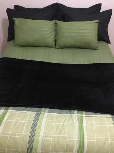 Cama con sábanas y almohadas verdes y negras en Adonai Copacabana Rooms 01, en Río de Janeiro