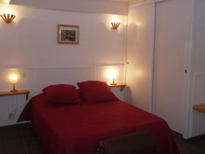 a bedroom with a red bed with two lamps at L'ancolie in Orelle