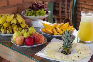 a table topped with plates of fruit and a drink at Pousada Búzios Garden in Búzios