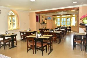 KSTDC Hotel Mayura Sudarshan ,Ooty في أوتي: مطعم فيه طاولات وكراسي في الغرفة