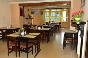 KSTDC Hotel Mayura Sudarshan ,Ooty في أوتي: مطعم بطاولات خشبية وكراسي وزهور