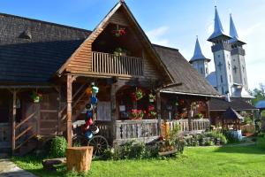 une vieille maison avec une église en arrière-plan dans l'établissement Pensiunea Maramu, à Breb