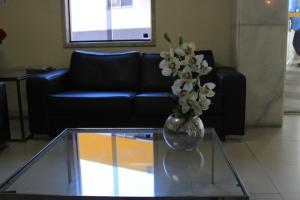 un vase avec des fleurs blanches assises sur une table en verre dans l'établissement Hotel Pirâmide Rodoviária, à Salvador