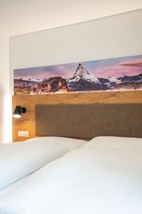 een slaapkamer met een bed met een schilderij aan de muur bij Apartments Patricia in Zermatt