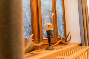 una vela de cristal en el alféizar de una ventana con cuernos de ciervo en Das kleine Bio Hotel Tiefenbach, en Schladming