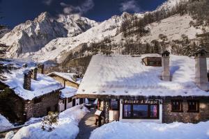 un edificio ricoperto di neve con una montagna sullo sfondo di Hotel Pilier D'Angle & Wellness a Courmayeur