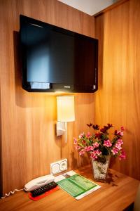 een kamer met een tv en bloemen op een tafel bij Hotel Domblick Garni in Keulen