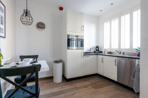 a kitchen with white cabinets and a table with a chair at Zeehuis Zandvoort in Zandvoort