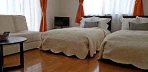 a bedroom with two beds and a couch and a television at La Curación in Naoshima