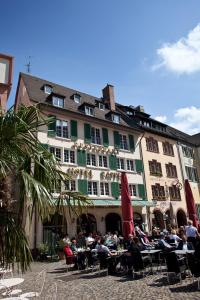 un groupe de personnes assises à des tables devant un bâtiment dans l'établissement Hotel Rappen am Münsterplatz, à Fribourg-en-Brisgau