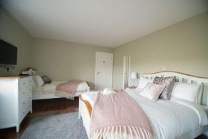 una camera da letto con un grande letto bianco con cuscini rosa di West Haven House a Doolin