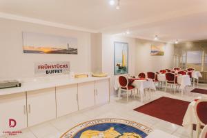 a dining room with white tables and chairs and a restaurant at Hotel Carolinensiel Doan in Carolinensiel