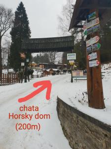 un letrero de la calle en la nieve con una flecha roja en Horsky dom, en Levoča