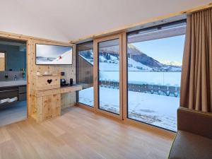 um quarto com grandes janelas com vista para as montanhas cobertas de neve em Alpeiner - Nature Resort Tirol em Neustift im Stubaital