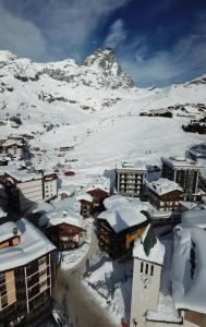 uma cidade coberta de neve com uma montanha ao fundo em Hotel Meynet em Breuil-Cervinia