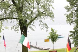 un albero con bandiere di fronte a un corpo idrico di Osteria La Riva a Locarno