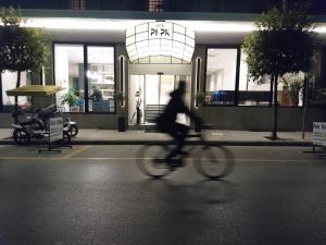 eine Person, die vor einem Gebäude Fahrrad fährt in der Unterkunft Hotel Park in Larisa